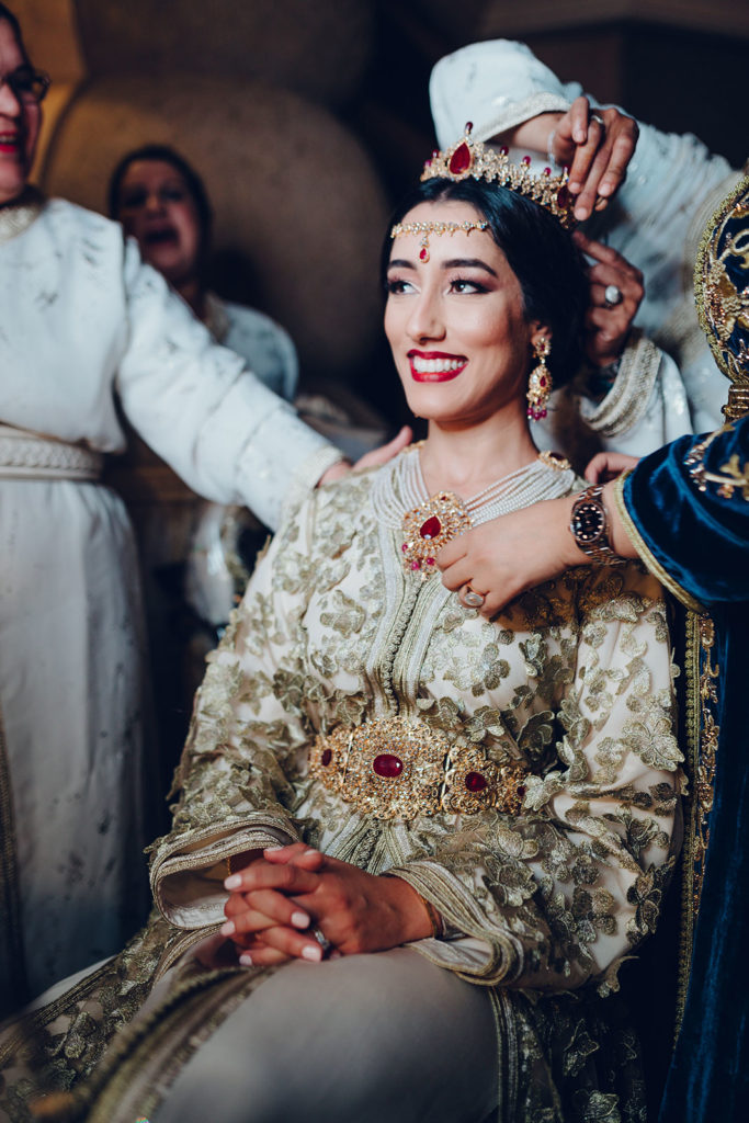Smiling bride wearing traditional embroidered attire during a cultural wedding ceremony, captured by international wedding photographer