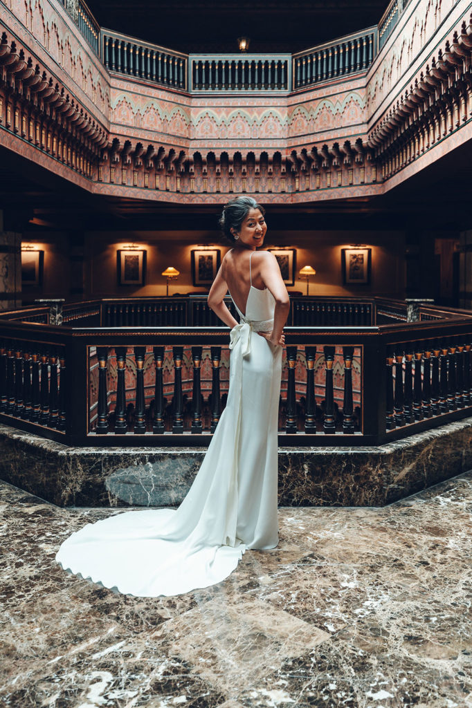 Bride in minimalist dress posing in elegant venue with architectural details, shot by luxury destination wedding photographer